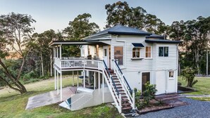 A two-story house with a covered porch and a staircase leading to the upper floor. - Lakeview Cottage in Mooloolah Valley: Pool & Sauna (Mooloolah Valley)
