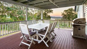 A covered outdoor deck with a table and chairs, overlooking a scenic landscape. - Lakeview Cottage in Mooloolah Valley: Pool & Sauna (Mooloolah Valley)