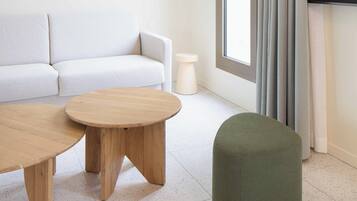 A modern living room with a sofa, a round wooden coffee table, and a green ottoman.