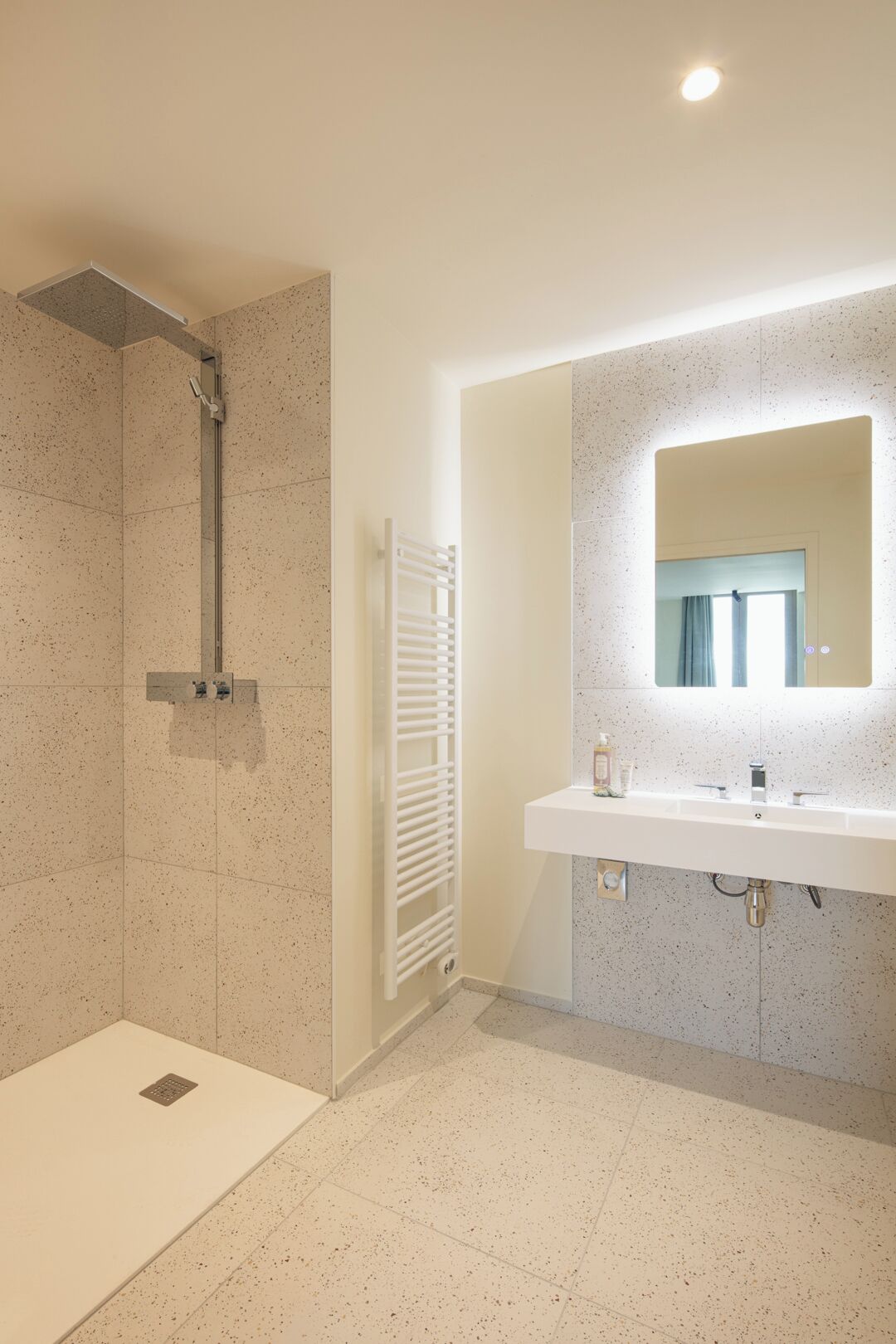 A modern bathroom with a shower, a white sink, and a mirror.