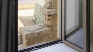 A view from a room with a sliding glass door to the beach, featuring a stone balustrade and a tiled floor. - Hôtel La Suite (Biarritz)