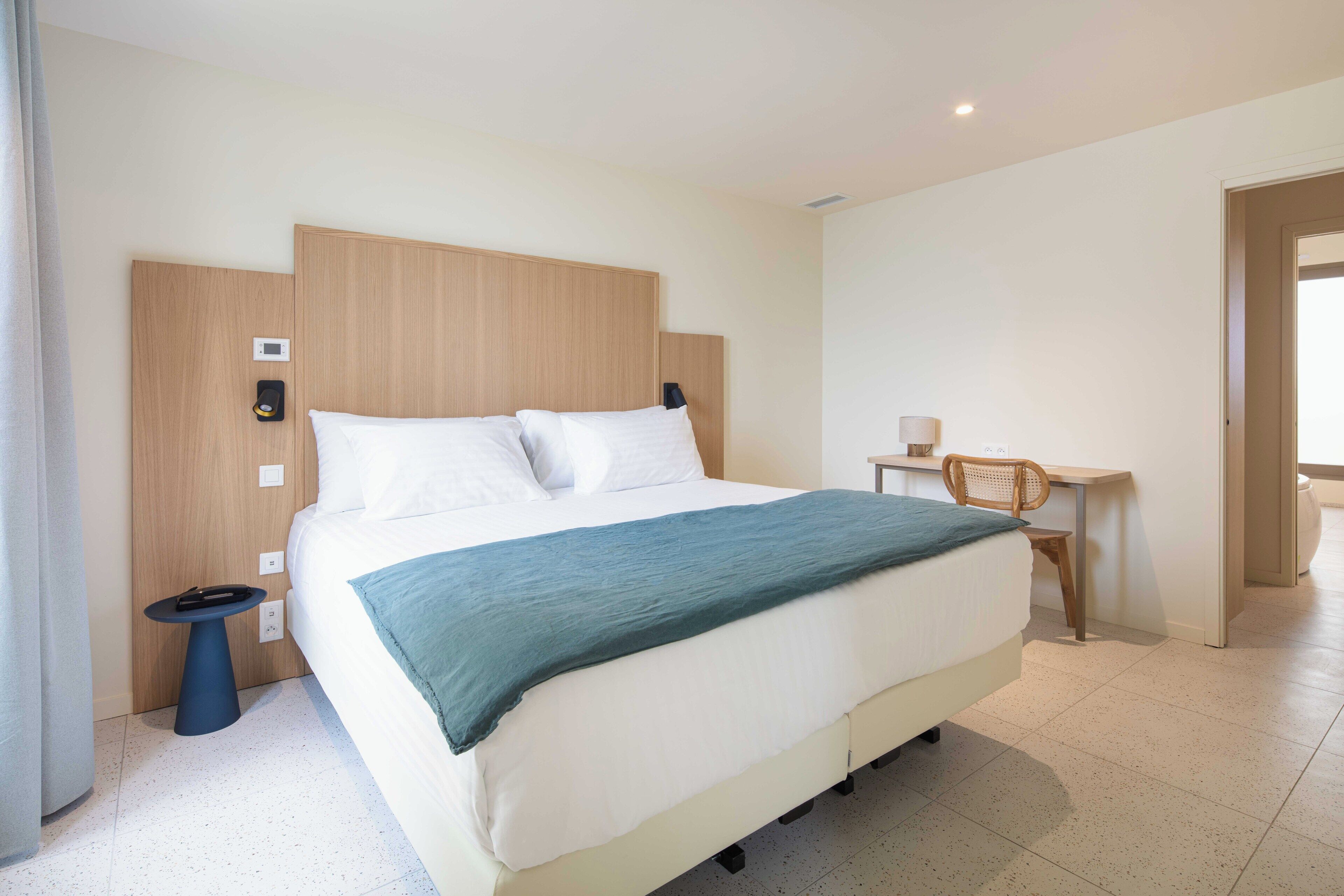A hotel room with a large bed, a desk, and a chair.