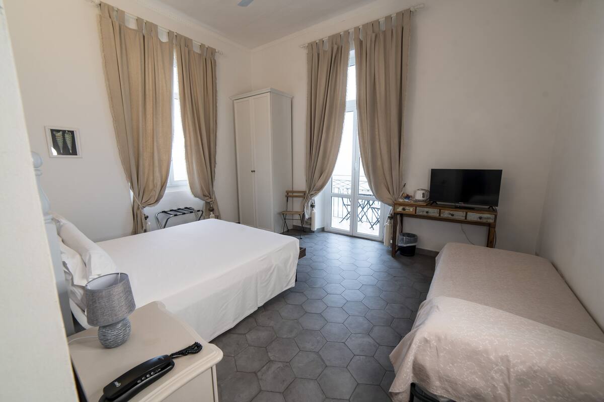 Habitación de hotel con dos camas, televisión, escritorio y armario.