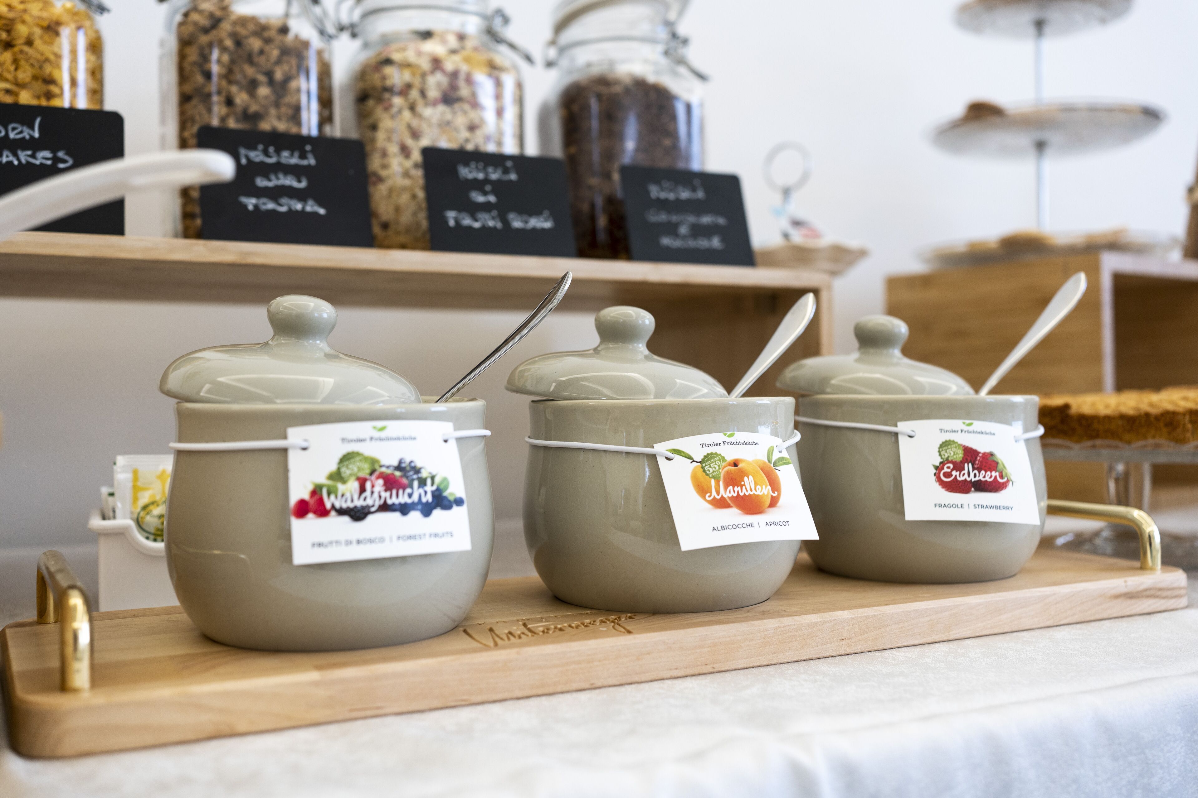 Three jars of preserves on a wooden tray with labels.