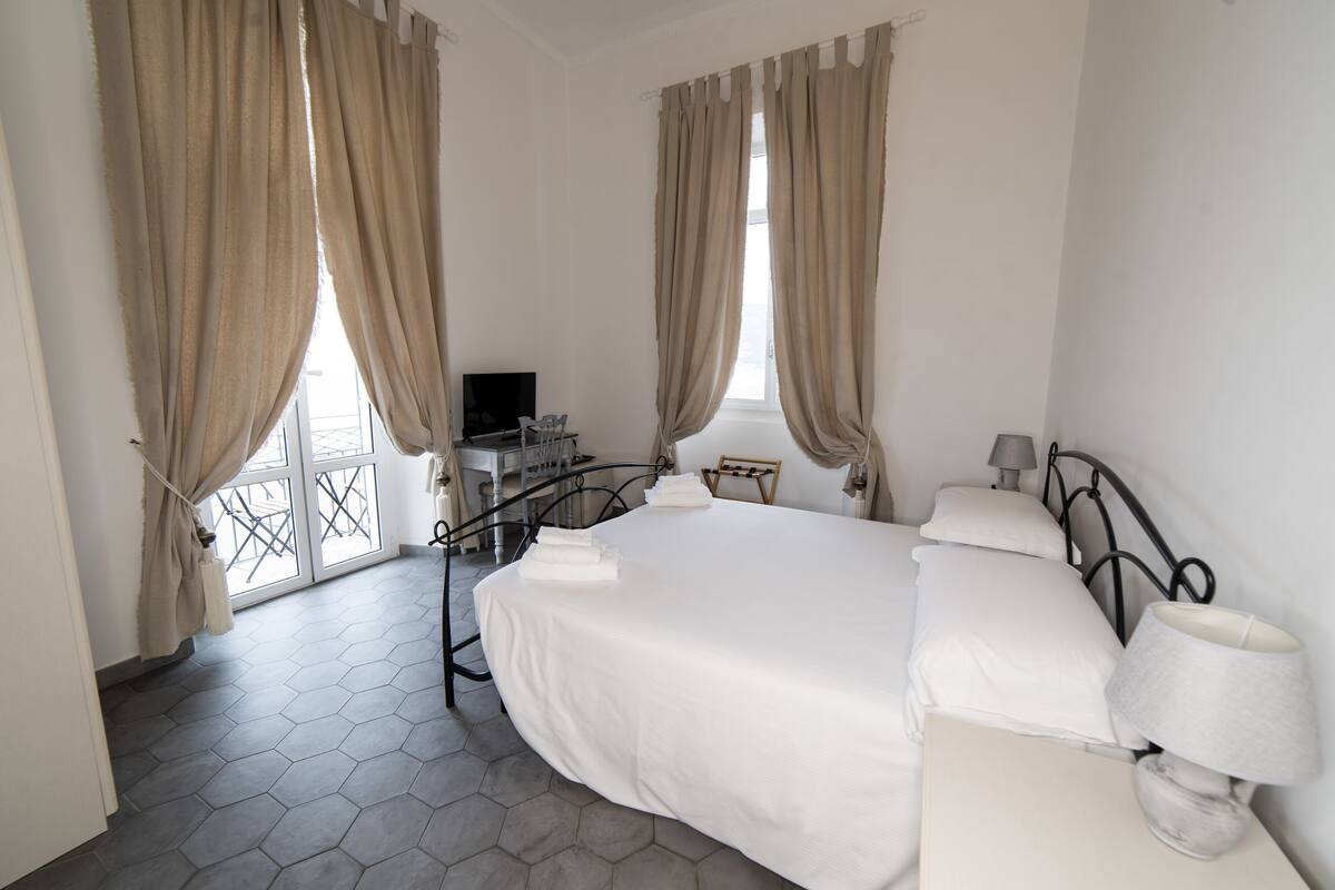 Una habitación de hotel con cama, televisión, escritorio y balcón.