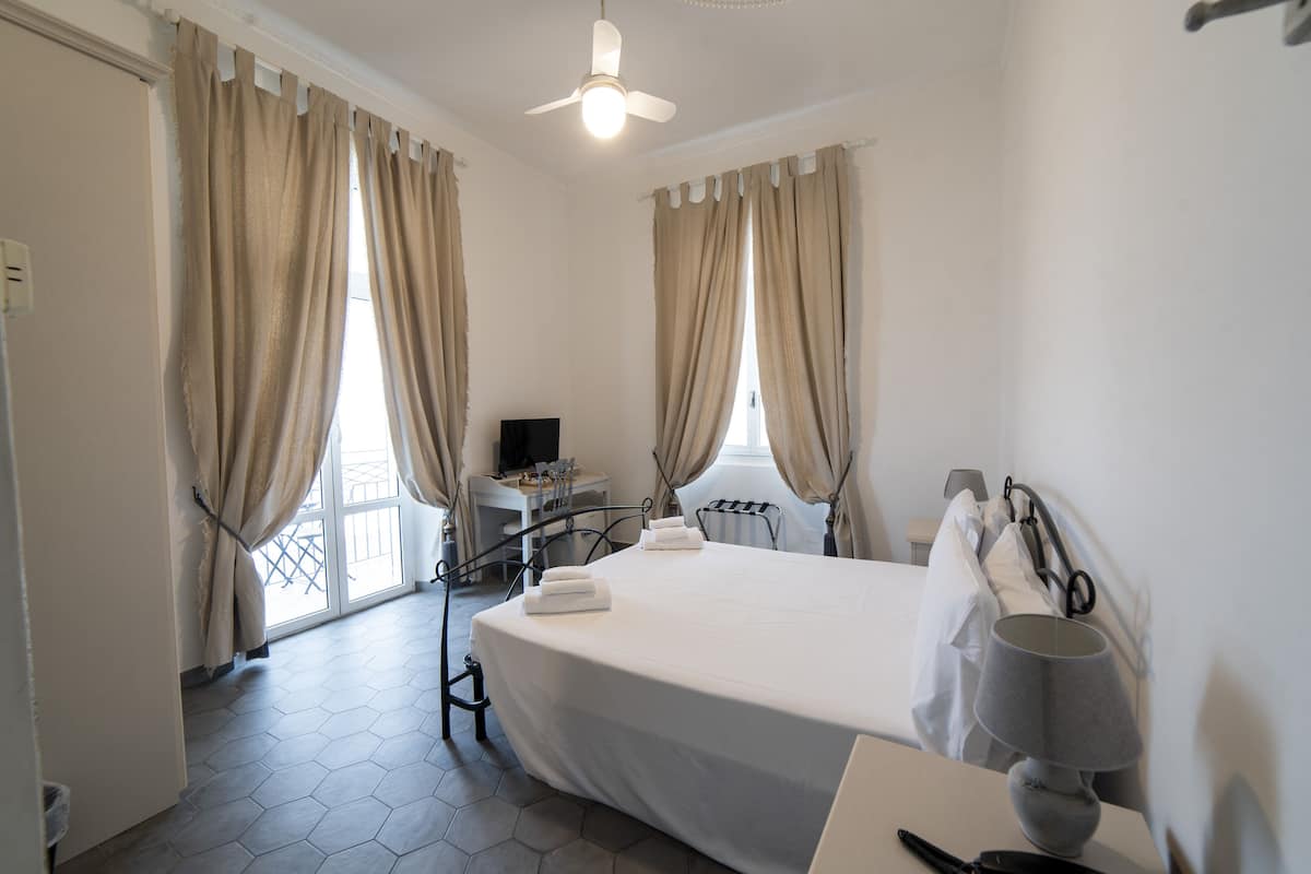 Una habitación de hotel con una cama, un escritorio, una silla, una lámpara y cortinas.