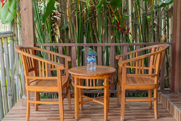Una mesa de madera con dos sillas sobre un suelo de baldosas, rodeada por una valla de bambú.