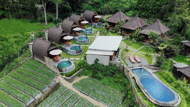An aerial view of a resort with multiple bungalow-style accommodations, a central pool, and surrounding lush greenery. - Cabana Bali Villa (Kintamani)