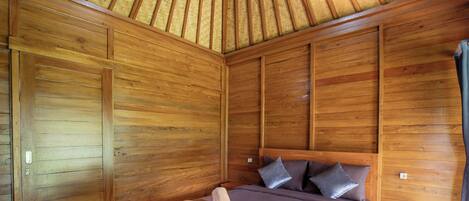 A wooden-paneled bedroom with a bed, pillows, and a nightstand.