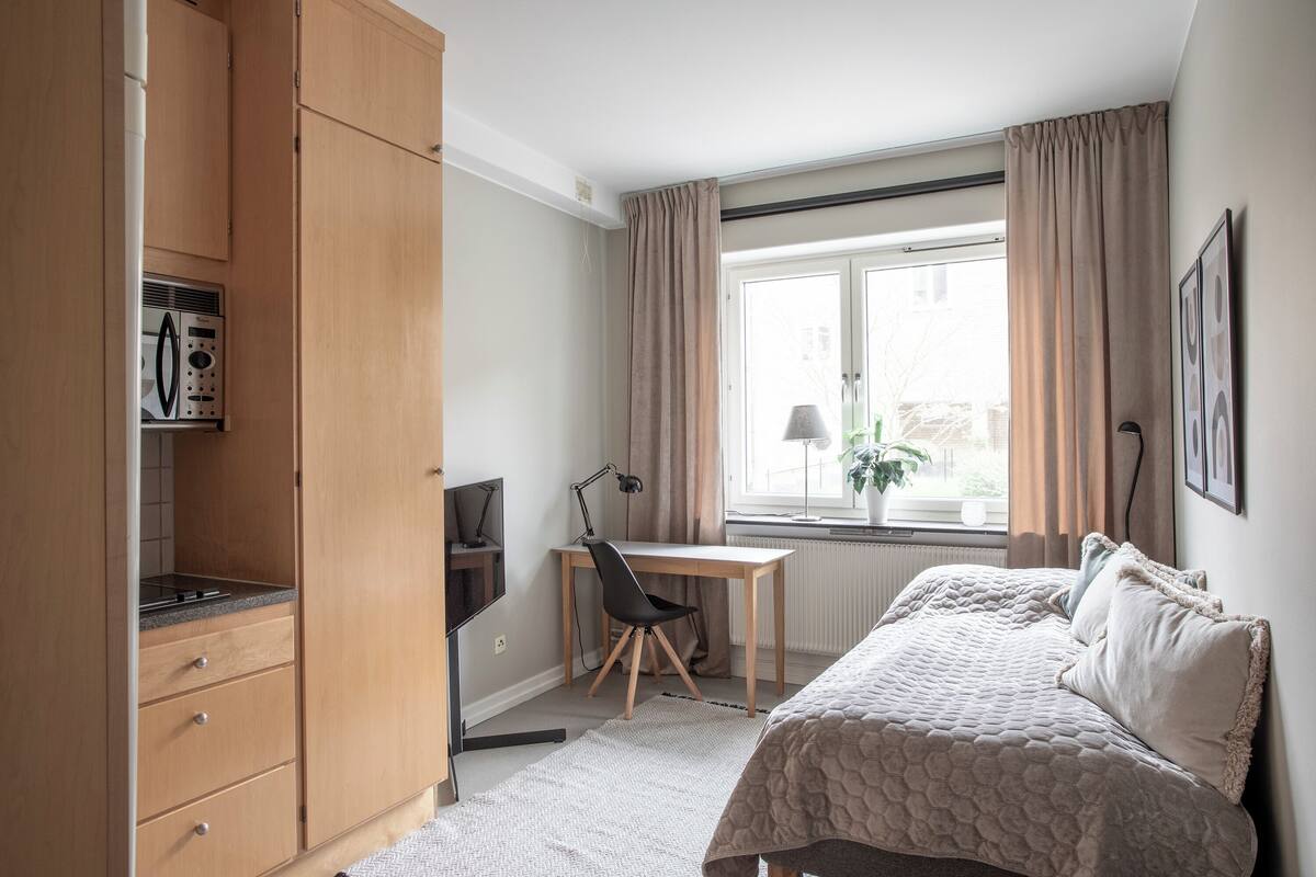 A bedroom with a bed, a desk, and a wardrobe.