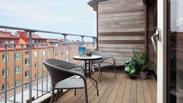 A balcony with wicker chairs, a small round table, and potted plants.