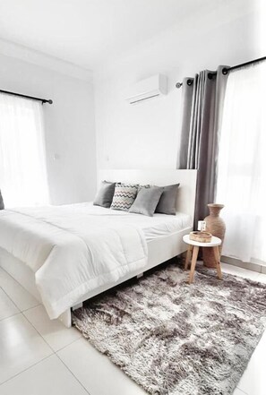 A modern bedroom with a large bed, a fluffy rug, and a small wooden side table. - Shortlet Homes Port Harcourt (Port Harcourt)