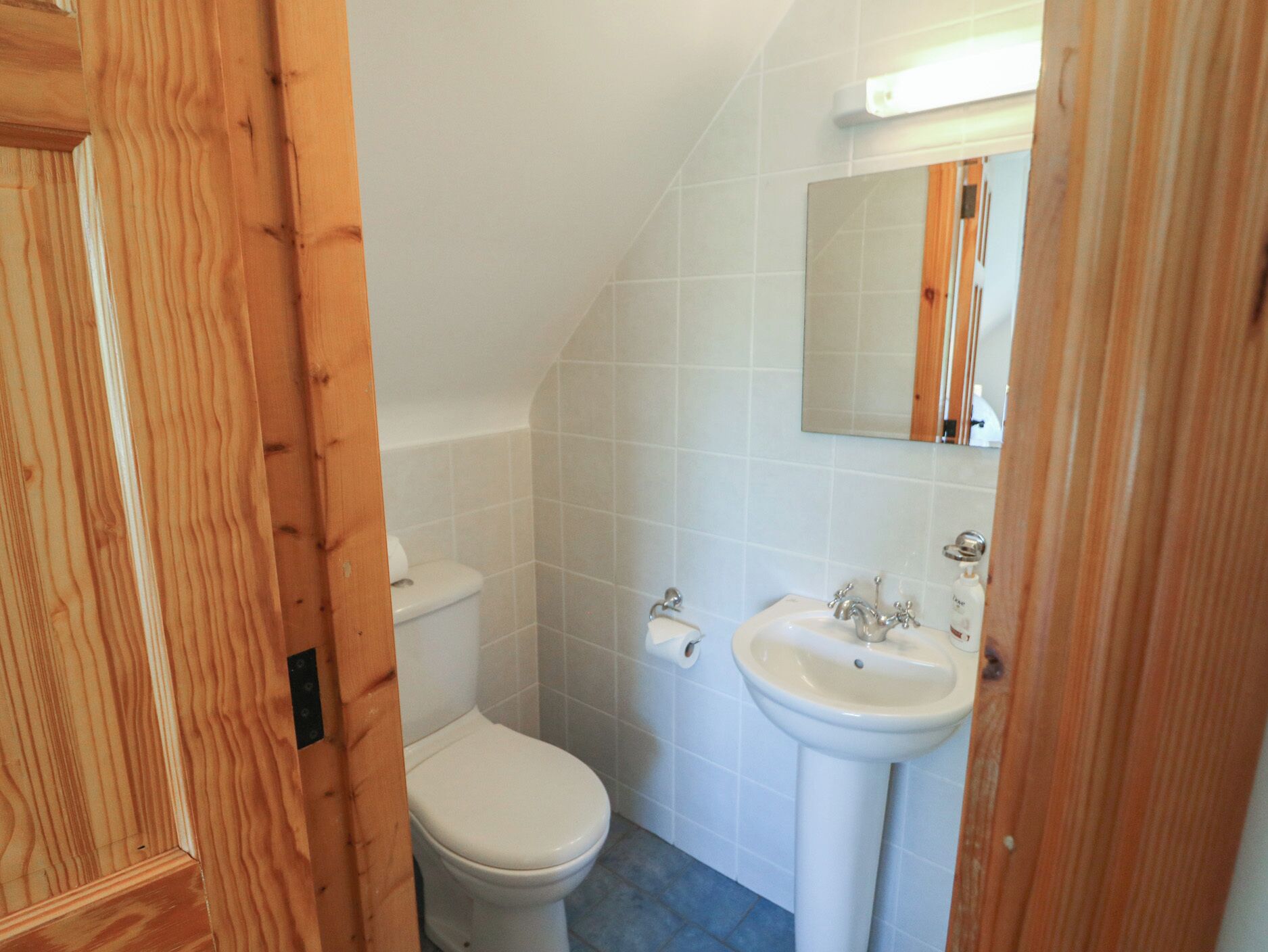 A small bathroom with a toilet, sink, and mirror.