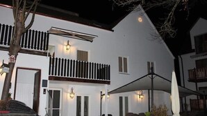 Un bâtiment blanc à deux étages, doté d’un balcon, d’un espace extérieur aménagé pour s’asseoir et d’une terrasse couverte.