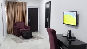 A modern hotel room with a black desk, a red chair, a television, and a large window. - De Primtex HOtel Portharcourt (Port Harcourt)