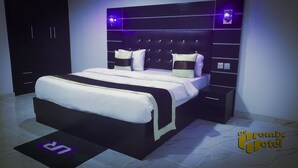 A modern bedroom with a large bed, bedside tables, and a headboard with built-in lighting. - De Primtex HOtel Portharcourt (Port Harcourt)