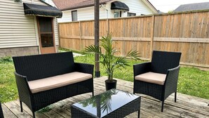 An outdoor patio with two black wicker sofas with beige cushions, a glass-top coffee table, and a potted plant. - The Boho Oasis: Spacious Deluxe Apartment, Close to All Amenities, Safe & Quiet (Windsor)