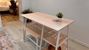 A modern, minimalist room with a wooden table and bench, a small potted plant, and a decorative wall piece. - The Boho Oasis: Spacious Deluxe Apartment, Close to All Amenities, Safe & Quiet (Windsor)