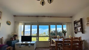 A living room with a TV, sofa, coffee table, and dining area with chairs. - Casa Primera Línea en Berria - Chalet Pitu 17801 (Berria)