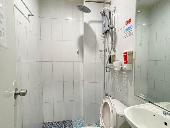 Une petite salle de bain avec des toilettes, un lavabo et une douche.