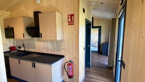 A wooden interior with a kitchen area, a fire extinguisher, and a sign indicating an exit. - CABAÑAS O RECUNCHO DO SOR. SETENTRIÓN (San Fiz)