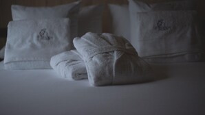 A neatly made bed with two folded white towels and two pillows with embroidered text. - CABAÑAS O RECUNCHO DO SOR. SETENTRIÓN (San Fiz)