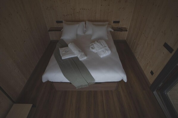 A bed with white linens, two pillows, and two towels folded on it.