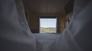 A bedroom with a large window, wooden walls, and a bed with white bedding. - CABAÑAS O RECUNCHO DO SOR. SETENTRIÓN (San Fiz)