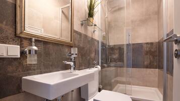 Een moderne badkamer met een wastafel, toilet en douche.