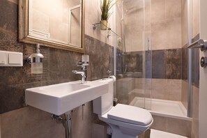 Une salle de bain moderne équipée d’un lavabo, de toilettes et d’une douche.