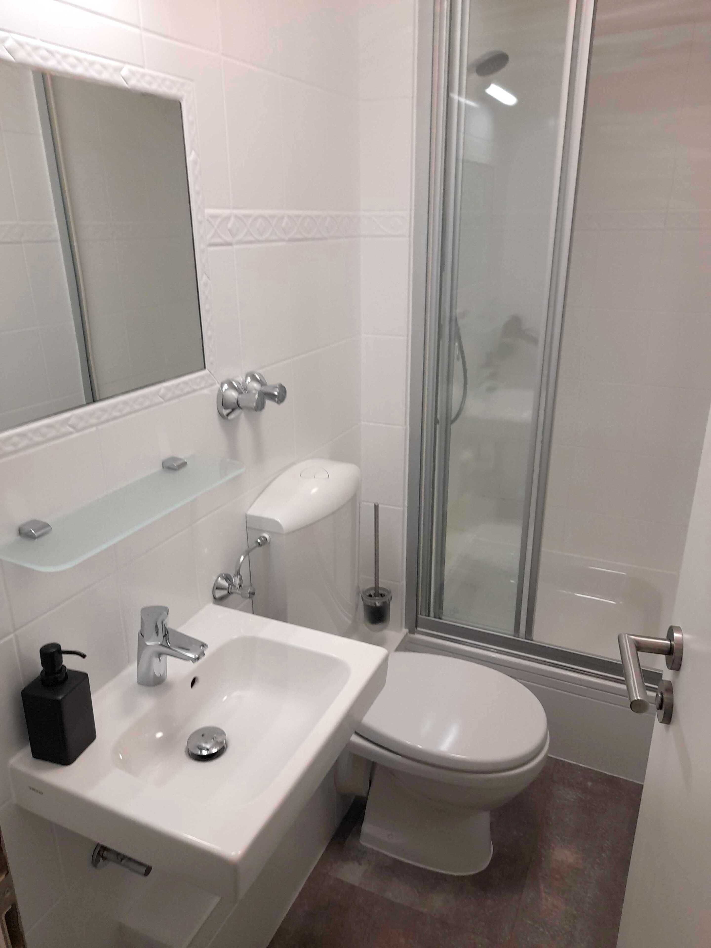 A bathroom with a sink, toilet, and glass shower enclosure.