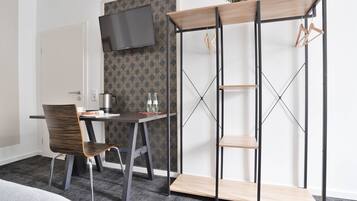 A modern hotel room with a desk, chair, and a TV mounted on the wall.