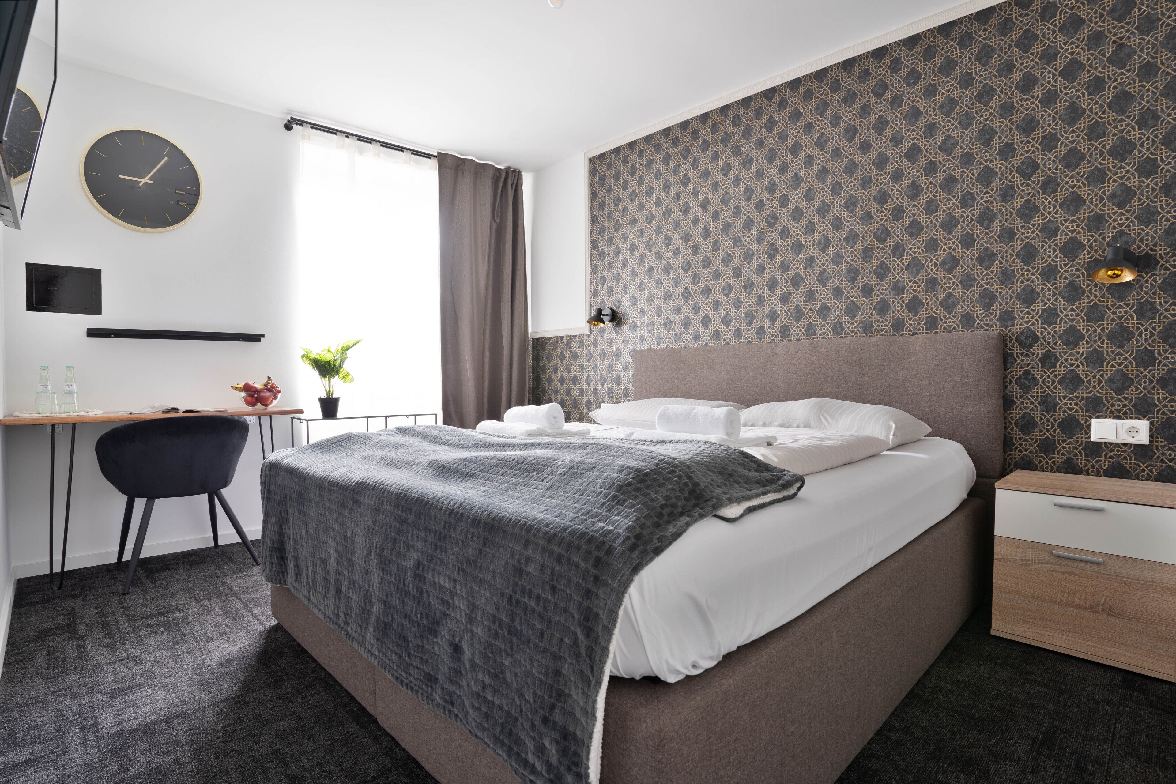 Una habitación de hotel moderna con una cama grande, un escritorio y una silla.