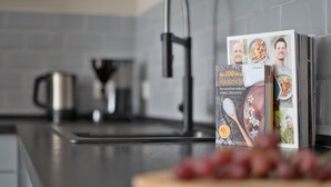 A kitchen with a modern faucet, a coffee maker, and a magazine rack with food magazines. - Stilvolle Apartments in Bonn I home2share (Bonn)