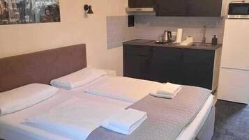 Quarto de hotel com uma cama, cozinha compacta e uma pintura com vista para a cidade.