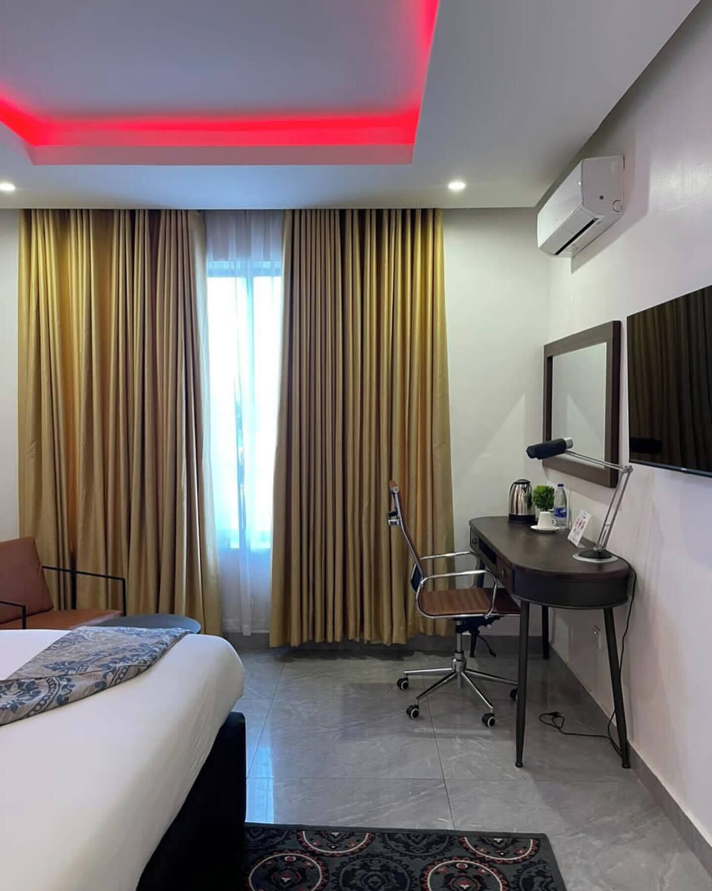 Una habitación de hotel con cama, escritorio, silla y cortinas.