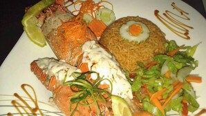 Ein Teller mit verschiedenen Speisen, darunter Fisch, Reis und Gemüse.