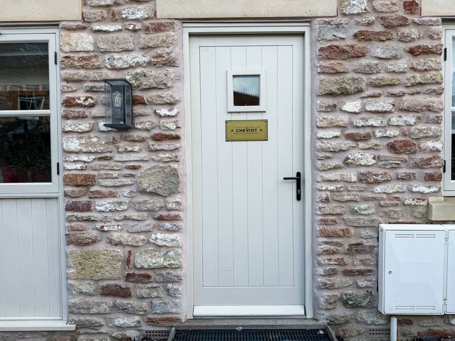 Un edificio in pietra con una porta bianca, una piccola finestra e un cartello sopra la porta.