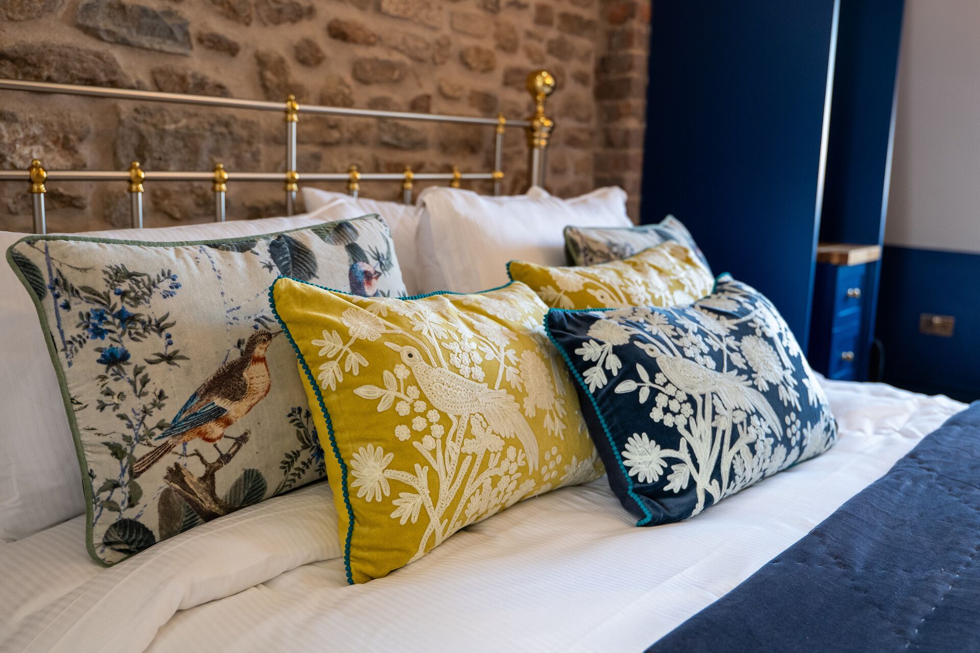 A bed with white linens and multiple decorative pillows with floral patterns.
