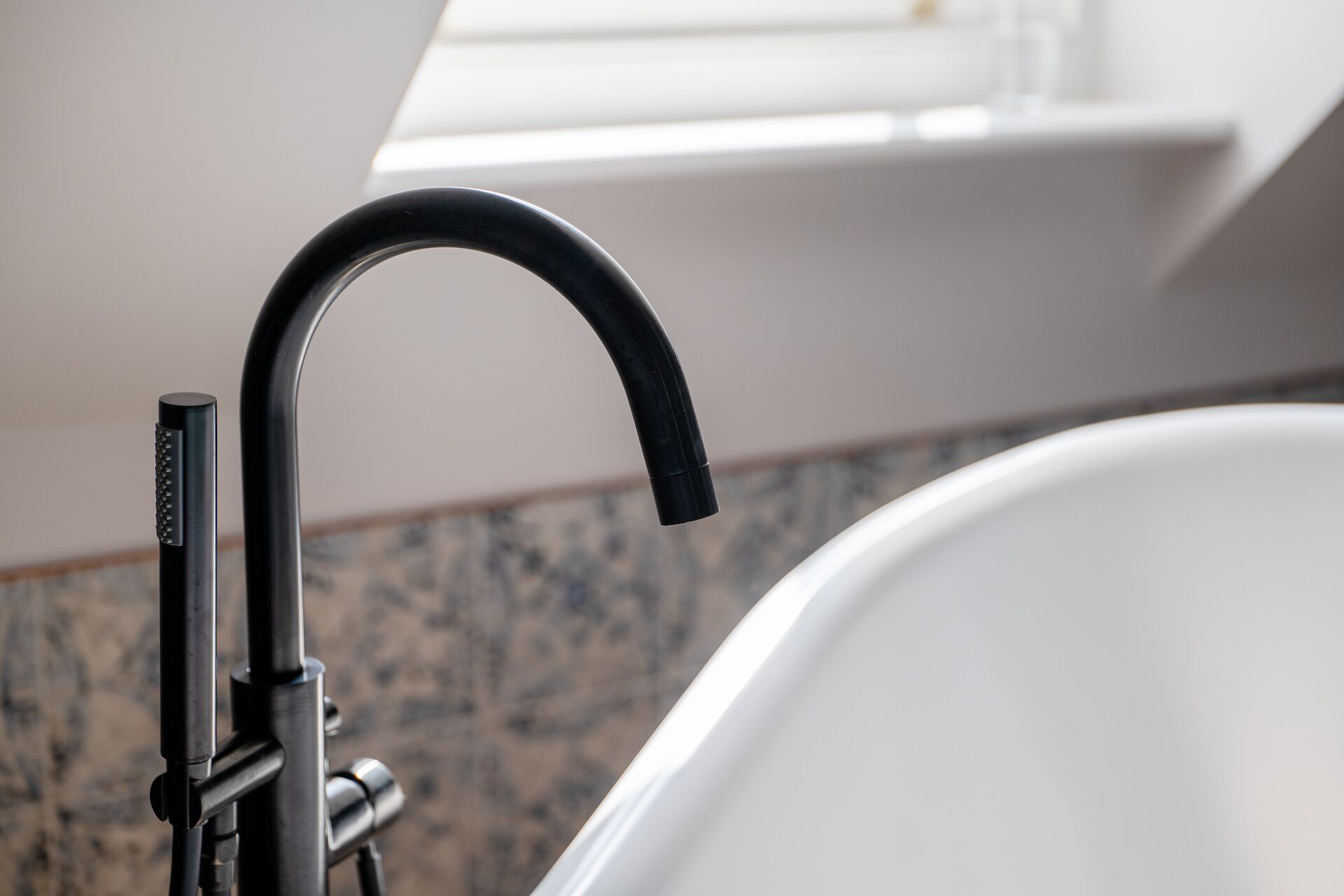 A modern bathroom with a black faucet and a white bathtub.