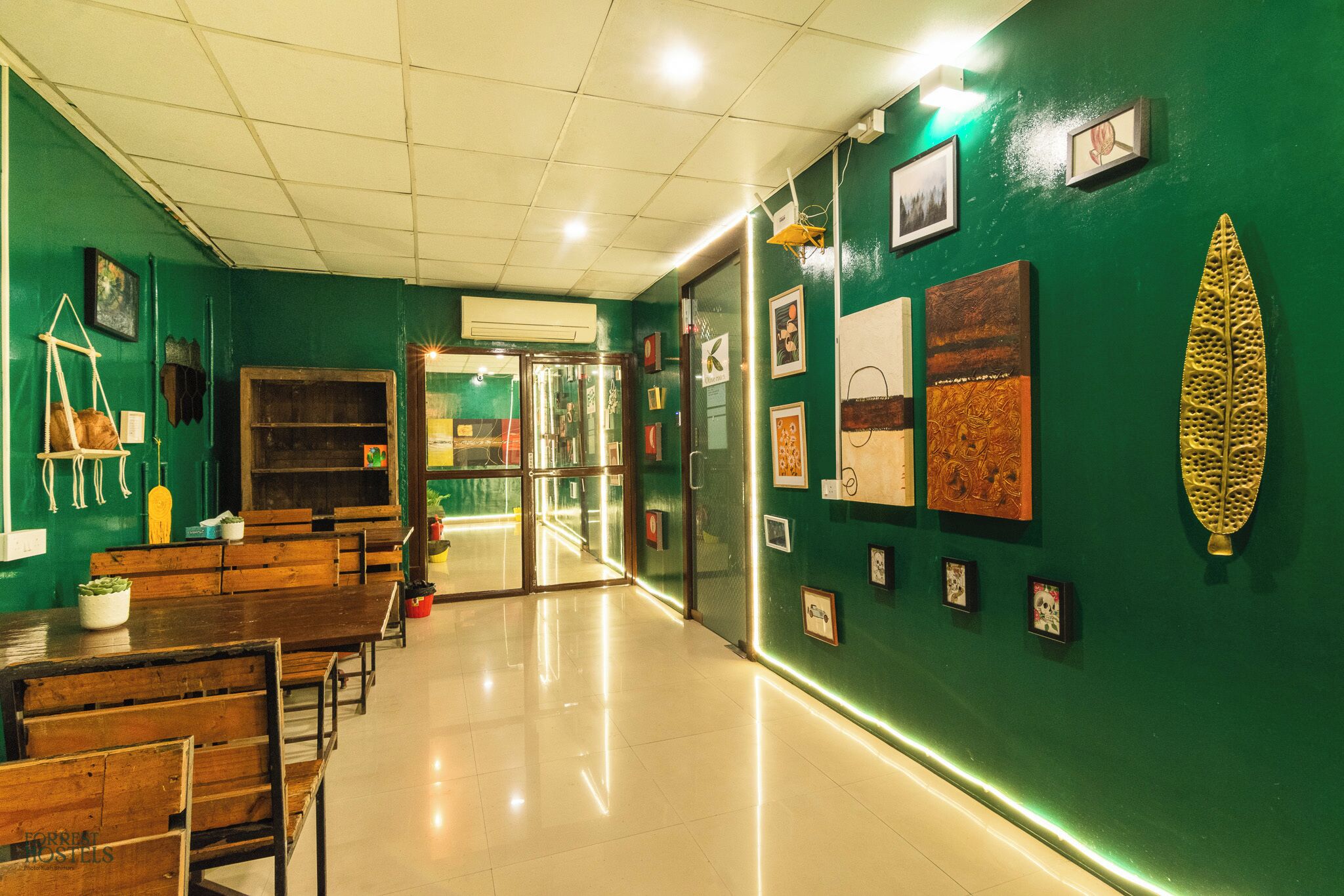 A room with green walls, wooden benches, and framed pictures on the wall.