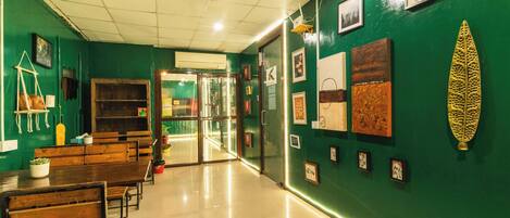 A room with green walls, wooden benches, and framed pictures on the wall.