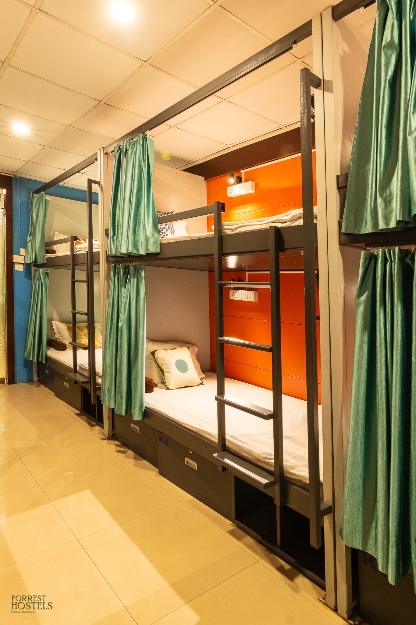 Bunk beds with green curtains, a tiled floor, and a wall-mounted shelf.