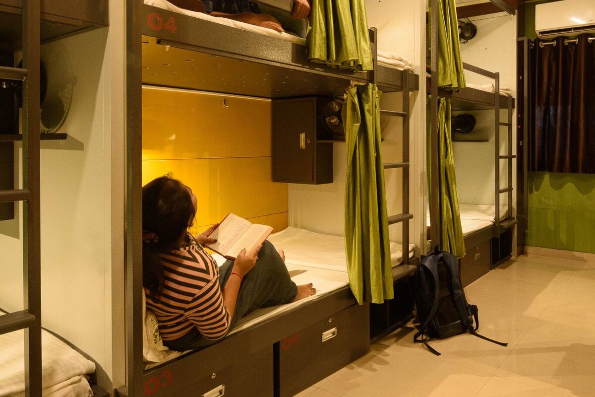 A dormitory room with bunk beds, a green curtain, and a suitcase on the floor.