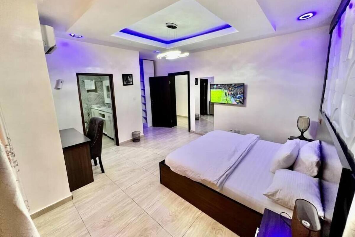 A modern bedroom with a large bed, a desk, and a television.
