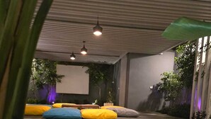 Ett utomhusområde med sittplatser, flera kuddar och en projektorduk.