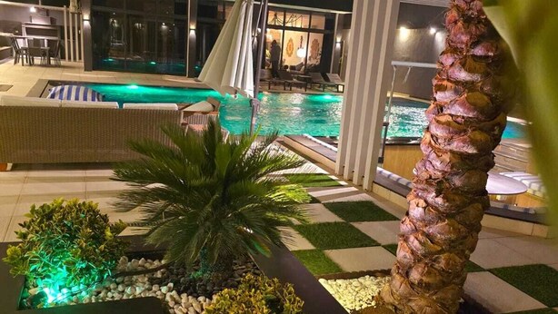 Ett modernt hotellområde med pool, en vattenrutschkana, solstolar och en palm.