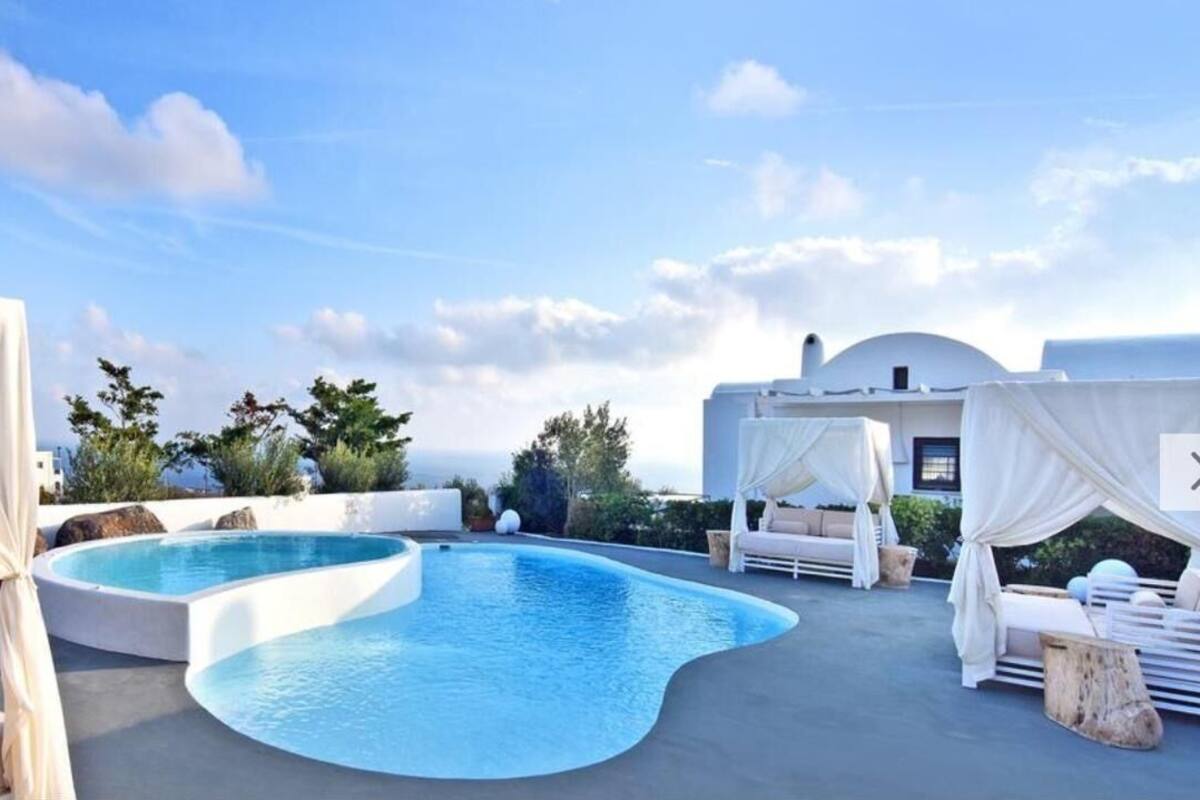 A rooftop pool area with a curved pool, white outdoor furniture, and a clear sky.