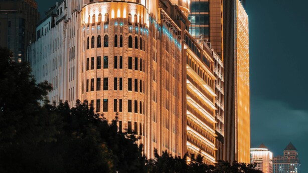 Un edificio histórico con una imponente torre de reloj y un moderno rascacielos a su lado.