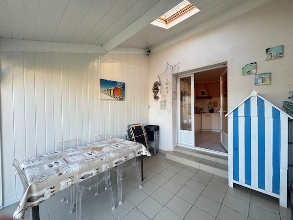 A dining area with a table set for four, a kitchen visible through an open door, and a blue and white striped structure.